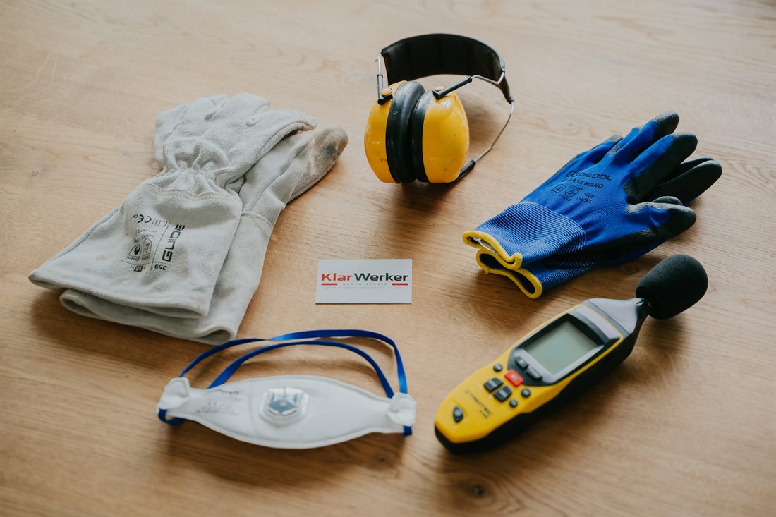 Persönliche Schutzausrüstung – Helm, Gehörschutz, Schutzbrille, Atemschutzmaske und Arbeitshandschuhe – bereitgelegt für den Arbeitsschutz im Betrieb